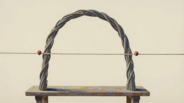 A woven willow arch on a wooden bench with a taut string crossing it at two red-marked points.