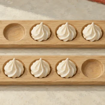Two wooden meringue boards, each with four meringues and two empty wells on opposite ends.