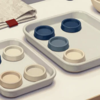 Two ivory trays hold separate groups of small blue and cream ceramic dishes.