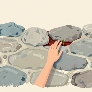 A fingertip presses into a gap in an old stone wall where crumbled mortar lets a green shoot push through.