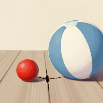 A big beach ball on sound boards beside a small red cannonball that has cracked the plank