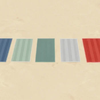 Beach towels laid edge to edge on the sand, seen from above, one red towel overlapping its neighbor
