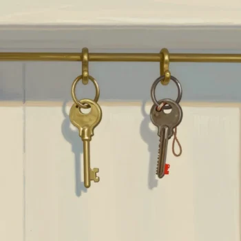 Two rings of keys hang inside a cupboard door, one bright and new, the other old, tarnished and tied with string.