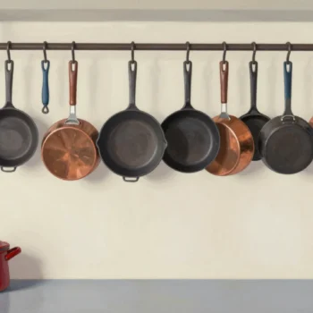 A kitchen pot rack tilting because every heavy pan hangs from one end, the other end's hooks empty.