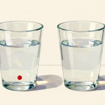 Two identical glasses of water, one with a red drop sinking in it
