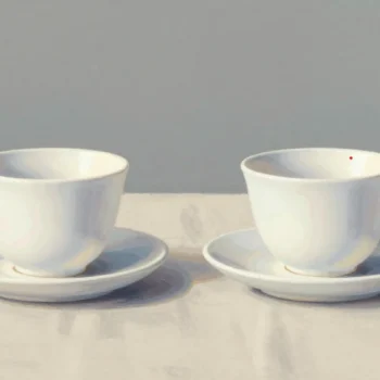 Two nearly identical white teacups on saucers, one with a small mark on its rim.