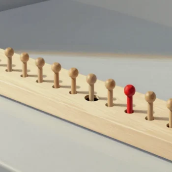 A long wooden peg board with a row of round pegs and one empty hole in the row, a red peg standing just past the gap.