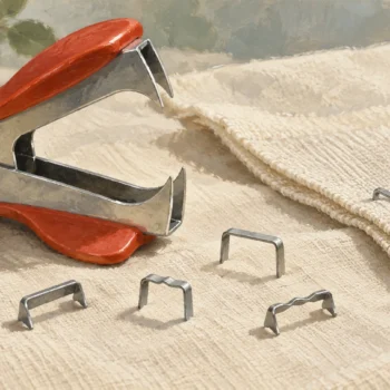 A staple remover exposes different metal staple shapes beside one intact fastening