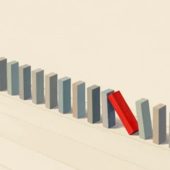 A line of falling wooden dominoes on a floor, with one red domino turned sideways to stop the chain.