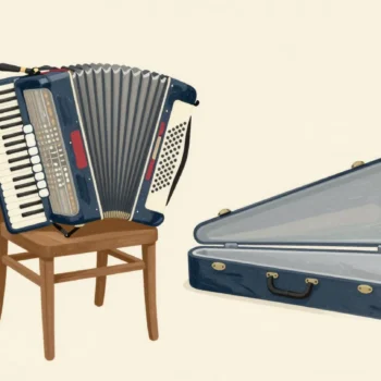 An accordion with its bellows squeezed shut by a red strap, resting beside its large open case