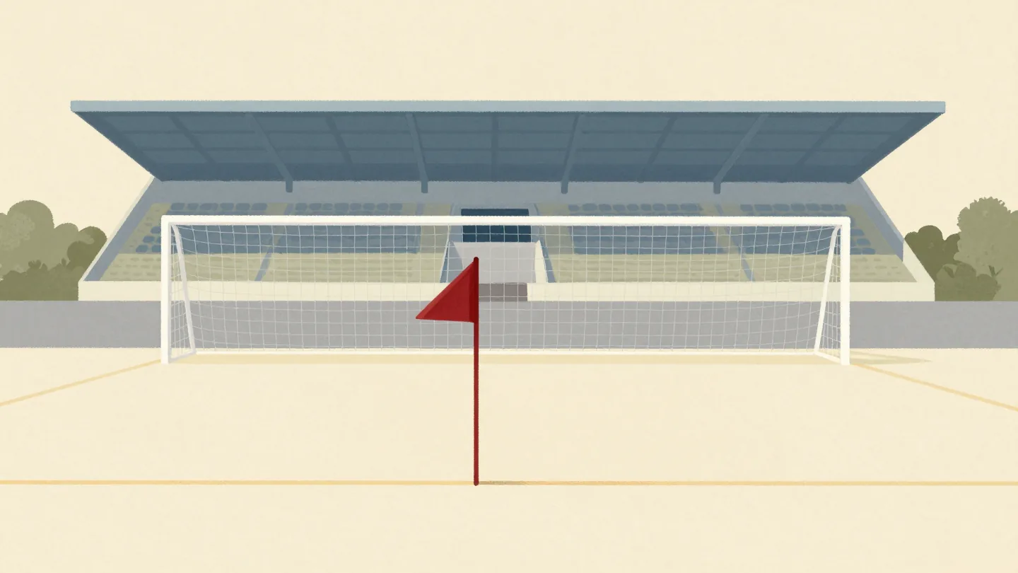 A practice football goal on a training pitch matching the stadium goal behind it, a red corner flag between