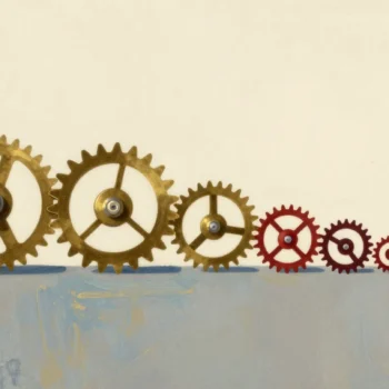 A row of meshed brass gears getting smaller, ending in a tiny red gear, one broken gear set aside