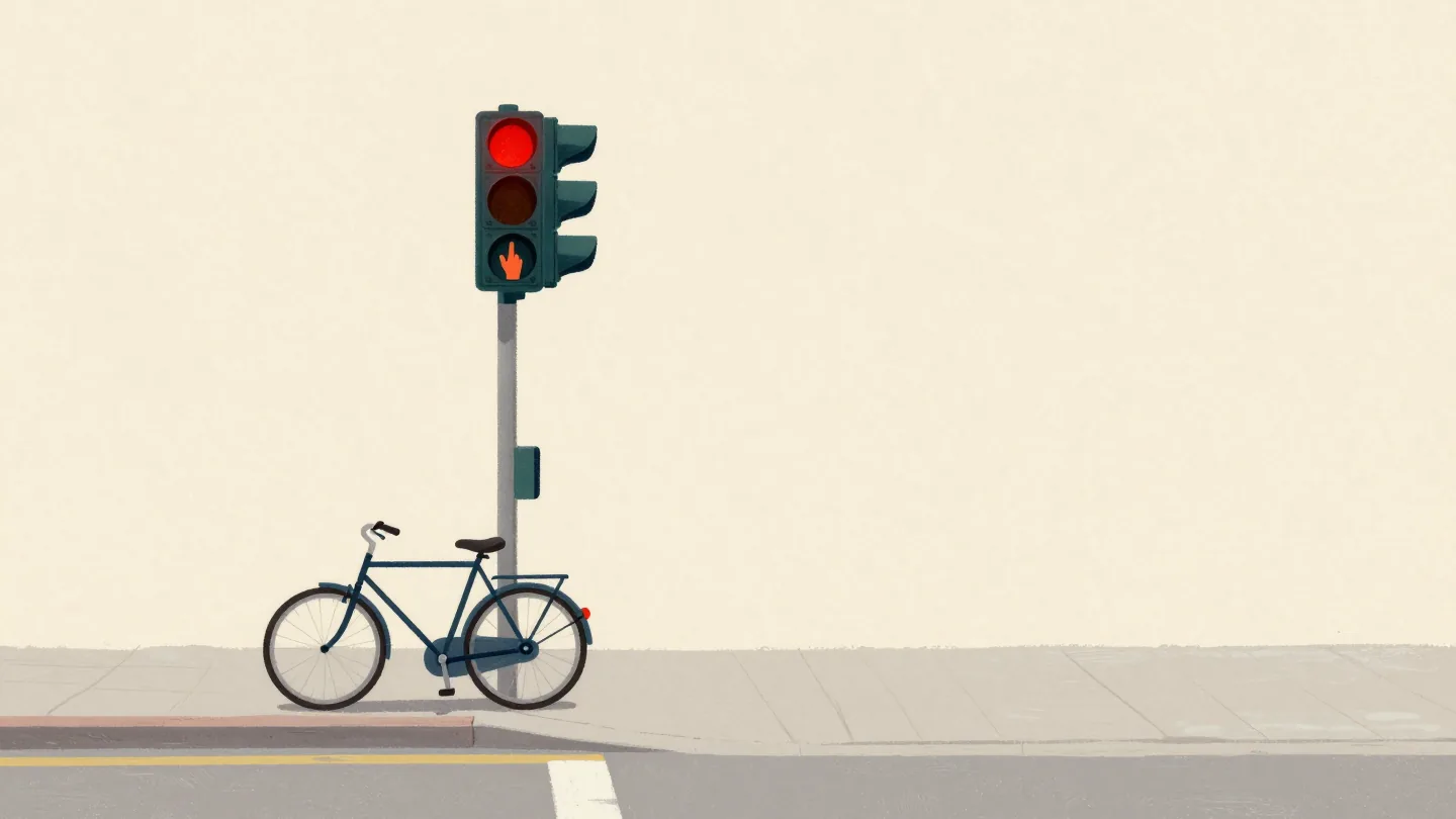A hand pressing a crossing button again, its small red wait lamp already glowing, a bicycle at the curb