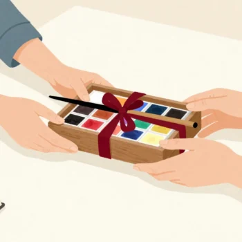 A new set of watercolor paints tied with a red ribbon handed across a desk