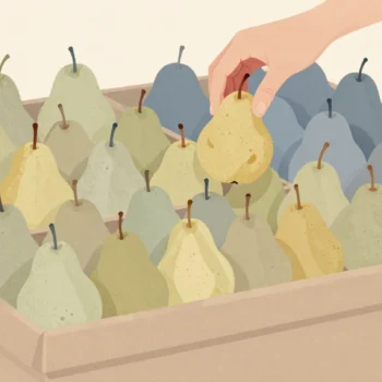 A hand lifts one pear from a crowded market fruit stall and gently presses it near the stem.