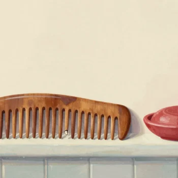 An old wooden comb on a bathroom shelf with gaps where some of its teeth have broken off.