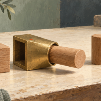 A square wooden piece passes through a brass adapter and emerges as a round piece