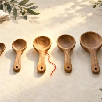 Seven wooden measuring spoons arranged by size with the middle spoon highlighted