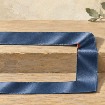 A slate blue fabric ribbon makes a physical fold onto a lower line