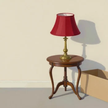 A hand fitting a new red lampshade onto an existing brass lamp base, a boxed new lamp pushed aside