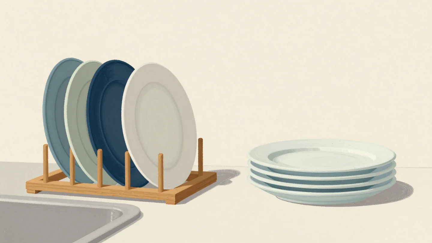 Clean plates wait on a drying rack beside a stack ready to put away
