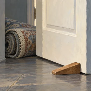 A doorstop holding an unattended heavy door and preventing a rug from passing