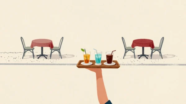 A hand carrying three drinks and a plate on one wooden tray across a cafe terrace, worn gravel paths behind.
