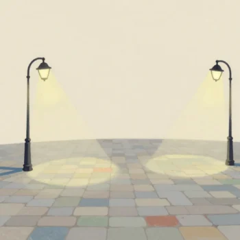Two street lamps on a cobbled square at night whose pools of light overlap in one brighter patch