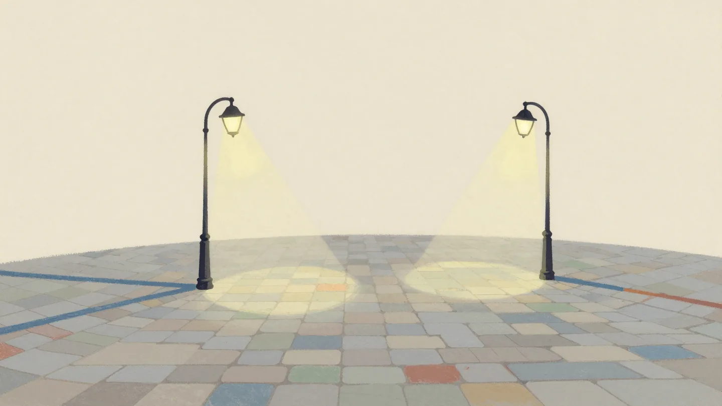 Two street lamps on a cobbled square at night whose pools of light overlap in one brighter patch