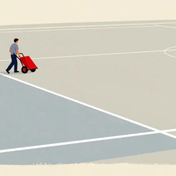 A groundskeeper pushing a line-marking cart across an empty field, painting the first boundary line.