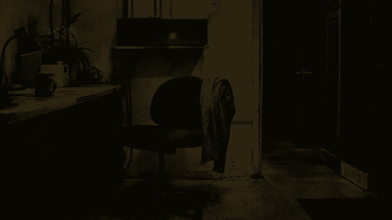 A single green indicator lamp glowing in a dark room above an empty chair at two in the morning