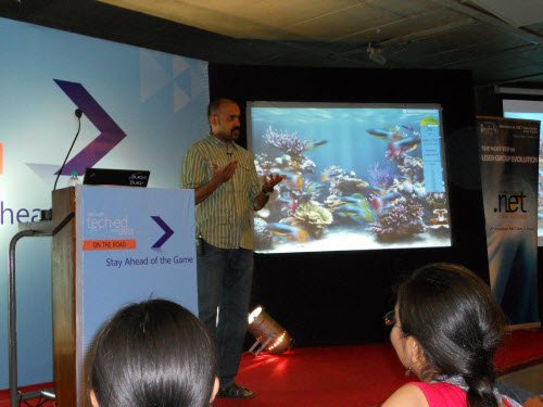 Man giving a presentation with a slide showing a coral reef.