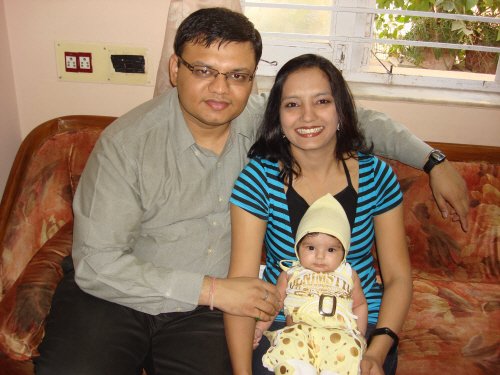 A couple and a baby on a couch.