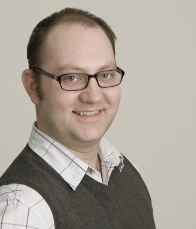 A man with glasses smiling.