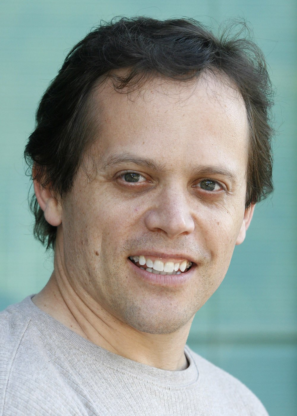 A friendly man in a grey sweater smiles.