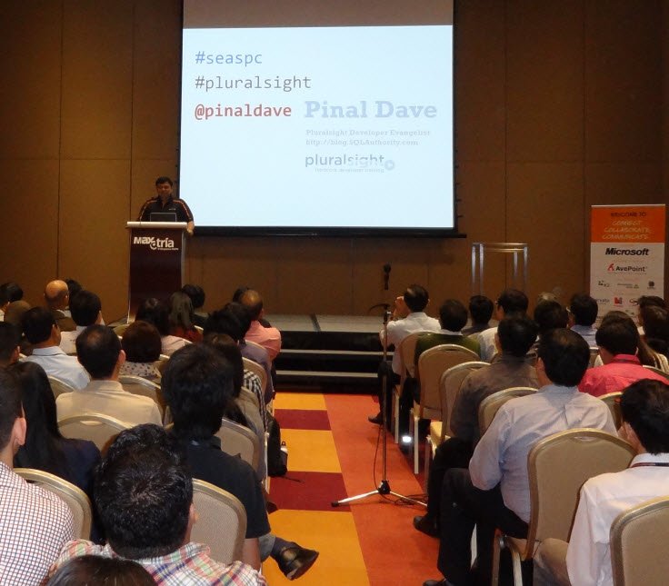 A speaker at a lectern in a conference hall full of attendees