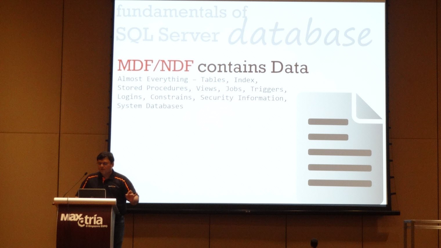 A presenter at a lectern next to a slide about SQL Server database files
