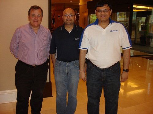 Three men standing in hallway.