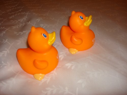 Two orange rubber ducks on a white sheet.