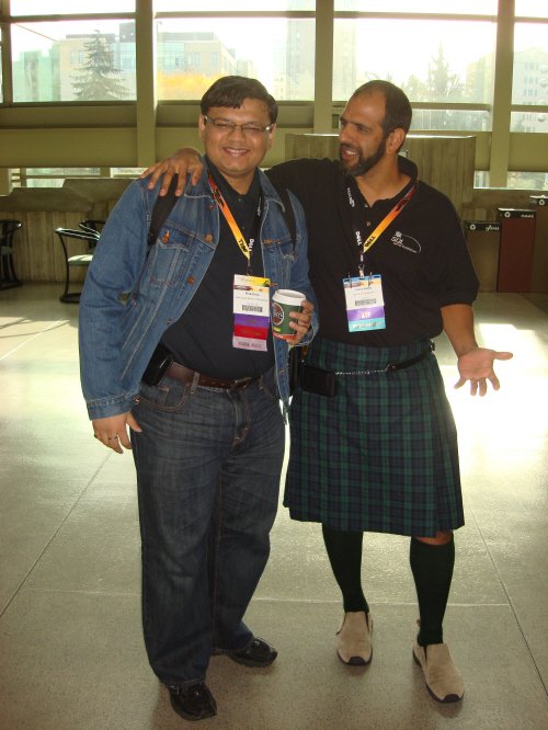 Two men wearing badges posing for photo.