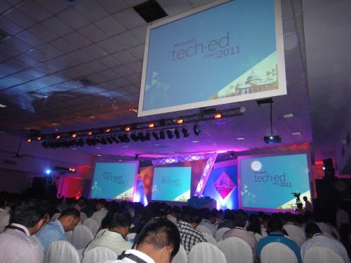 Audience in a large hall facing stage screens showing TechEd 2011