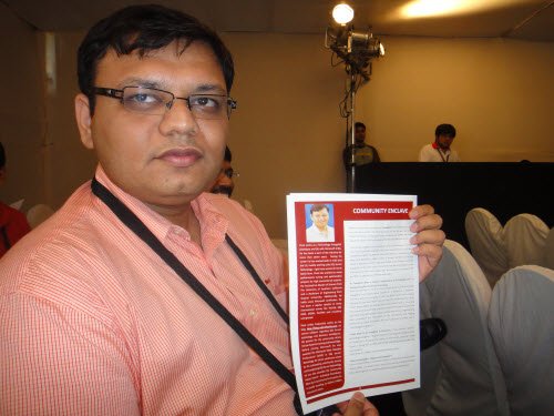 A person holds a document titled 'COMMUNITY COLLABORATE..
