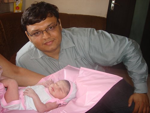 Man in blue shirt with newborn baby.