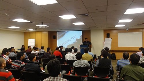 A presenter at the front of a room full of attendees at a SQL Server user group meeting