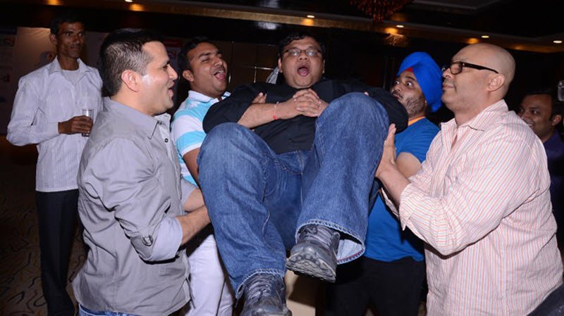 Group of men lifting another man.