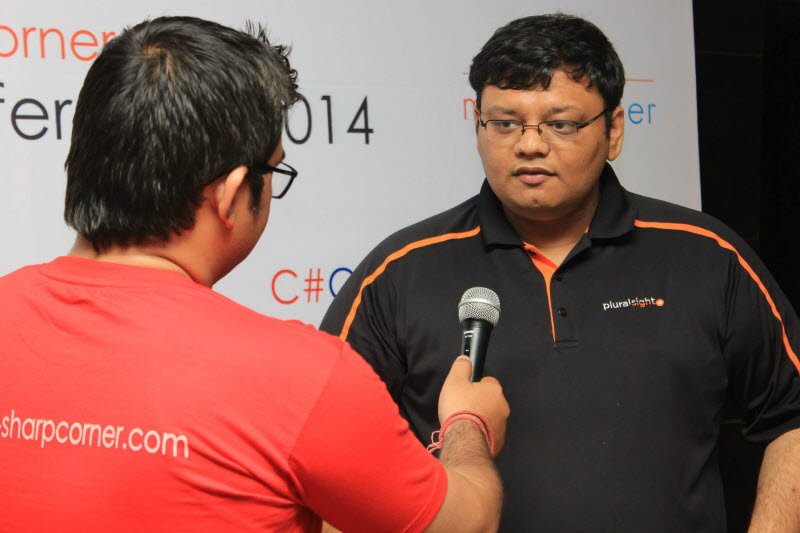 Man in black shirt with orange stripe being interviewed at C#0rner 2014 conference.