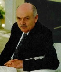A man in a suit sitting with his hands clasped.