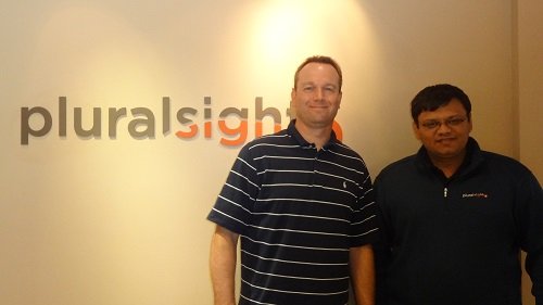 Two men standing in front of Pluralsight logo.