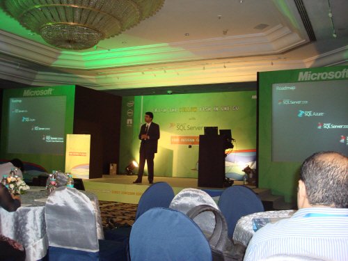A presenter speaks on stage at a Microsoft event.