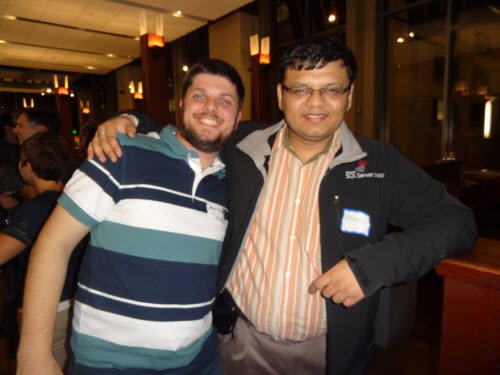 Two men smiling at camera at social event.
